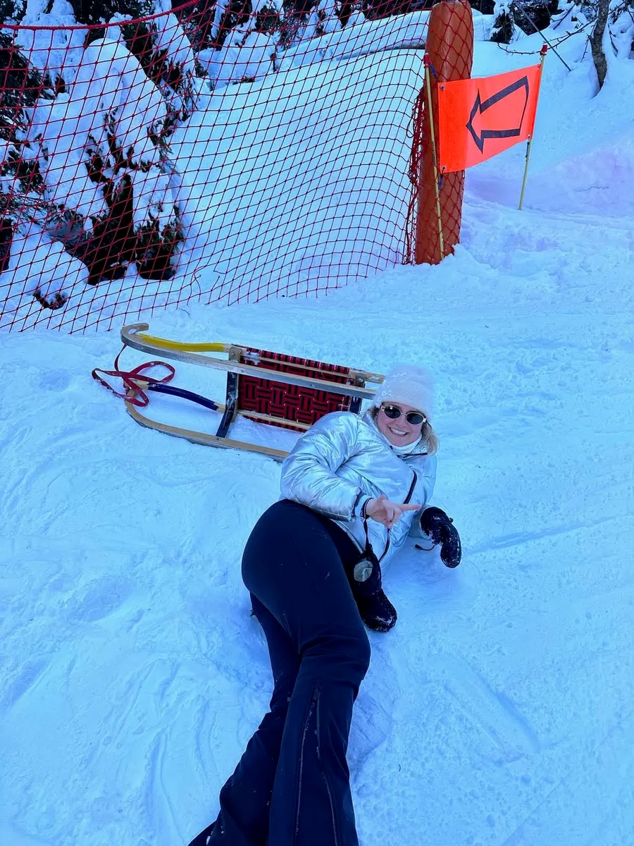 Marie ligger i snøen ved en kjelke.